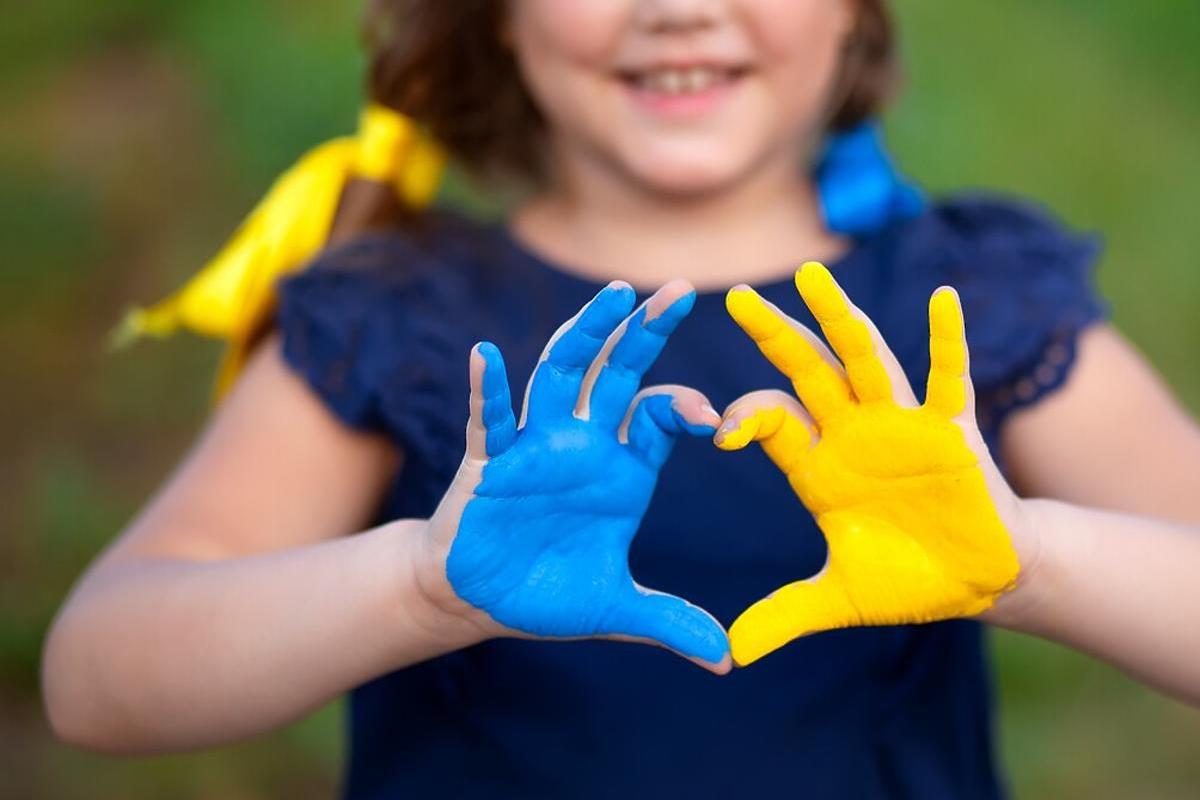 Синьо-жовті дитячі долоні, які роблять серце пальцями